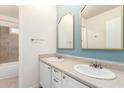 Updated bathroom with dual sinks, white cabinets, framed mirrors and a tiled tub/shower combo at 13148 N 21St Ave, Phoenix, AZ 85029