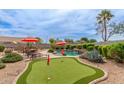 Beautiful backyard features a pool, putting green, patio furniture, and lush landscaping, ideal for outdoor living at 14374 W Amelia Ave, Goodyear, AZ 85395