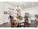 Open-concept dining area with a glass table, chandelier lighting, and seamless flow into the kitchen at 14374 W Amelia Ave, Goodyear, AZ 85395