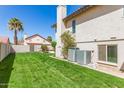 Well-manicured backyard featuring lush green grass, privacy fence, and exterior of house with dual air conditioning units at 1920 E Belmont Dr, Tempe, AZ 85284