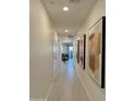 A long, brightly lit hallway with ceramic tile floors, doors, and elegant artwork adorning the walls at 20610 W Vermont Ave, Buckeye, AZ 85396
