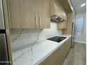 Close up of the kitchen countertop and cabinets, featuring a smooth cooktop and luxury white marble backsplash at 20822 N 42Nd. Ave, Glendale, AZ 85308