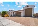 Home featuring a tile roof, arched entryway, desert landscaping, a three car garage, and a brick paved driveway at 25800 N 140Th Ln, Surprise, AZ 85387