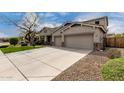 Charming home with a three-car garage and a concrete driveway surrounded by rocks and a tree at 30246 N 123Rd Ln, Peoria, AZ 85383