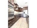 Modern kitchen with stainless steel appliances, dark cabinetry, granite countertops, and tile flooring at 3717 E Lodgepole Dr, Gilbert, AZ 85298
