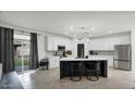 Bright kitchen with white cabinetry, stainless steel appliances, a spacious island, and sliding glass doors at 6818 W St Catherine Ave, Laveen, AZ 85339