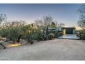 Desert home at dusk featuring a bridge leading to a garage, with thoughtful landscape lighting at 8644 E Sweetwater Ave, Scottsdale, AZ 85260