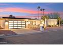 Contemporary home featuring a multi-car garage and stucco exterior complemented by desert landscaping at sunset at 9052 N 29Th St, Phoenix, AZ 85028