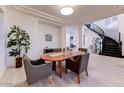 Bright dining room boasts an oval wood table, stylish chairs, and a view of the elegant staircase at 10843 E Acacia Dr, Scottsdale, AZ 85255