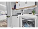 Functional laundry room featuring a modern washer and dryer set, storage cabinets, and wood-style flooring at 8972 E Arizona Park Pl, Scottsdale, AZ 85260