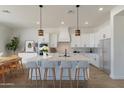 Elegant kitchen featuring white cabinetry, pendant lighting, a large island with seating, and stainless steel appliances at 10829 W Woodruff Rd, Casa Grande, AZ 85194