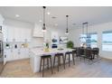 Bright open-concept kitchen featuring an island with seating and stylish lighting adjacent to a dining area at 10947 W Woodruff Rd, Casa Grande, AZ 85194