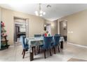 Bright dining room with tile floors, chandelier and a table set for six with blue chairs and a floral centerpiece at 15856 N 76Th Ave, Peoria, AZ 85382