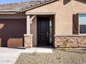 Close up of front entrance with a brown door and stone facade at 16076 W Prickly Pear Trl, Surprise, AZ 85387