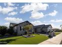 Well-maintained front yard with lush green grass, manicured trees, and a brick and stone facade at 19901 E Country Meadows Dr, Queen Creek, AZ 85142