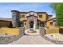 Exterior of home with stone accents and paved driveway, featuring an arched entryway with flowers at 3312 N 89Th Pl, Mesa, AZ 85207