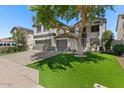 Inviting two-story home with a two-car garage, lush green lawn, and mature tree, offering a warm, welcoming feel at 9618 E Monterey Ave, Mesa, AZ 85209