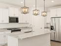 Modern kitchen with white cabinets, stainless steel appliances, granite countertops, and stylish lighting at 16015 W Desert Hollow Dr, Surprise, AZ 85387