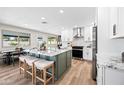 Bright kitchen with a large island, seating, white cabinets, stainless steel appliances, and wood floors at 1012 E Magdalena Dr, Tempe, AZ 85283