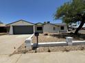 Charming single-story home with a gray garage door, xeriscaping and a well-maintained yard at 15243 N 52Nd Dr, Glendale, AZ 85306
