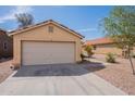 Beige single-story home featuring a two-car garage and a well-maintained front yard with desert landscaping at 168 S 223Rd Dr, Buckeye, AZ 85326