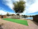 Backyard view of lake with faux grass area and gravel landscaping at 2409 N 112Th Ln, Avondale, AZ 85392