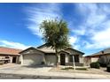 Charming home with a three-car garage, complemented by a mature tree and desert landscaping at 2409 N 112Th Ln, Avondale, AZ 85392