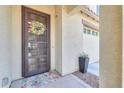 Close-up of a stylish front door adorned with a colorful wreath, a neutral mat and a decorative planter at 277 W Glacier Bay Dr, San Tan Valley, AZ 85140