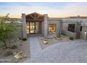 Modern home featuring a covered entry, desert landscaping, and stone driveway at 29599 N 106Th Pl, Scottsdale, AZ 85262