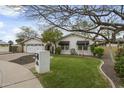 Inviting single-story home with a well-manicured lawn, mature trees, and white exterior at 6340 E Mitchell Dr, Scottsdale, AZ 85251