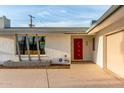 A lovely front entrance of a single story home with a red door and desert landscaping at 8750 E Starlight Way, Scottsdale, AZ 85250