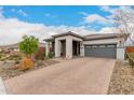 This lovely single-story home features brick driveway, neutral color palette, and desert landscaping at 8751 S 168Th Dr, Goodyear, AZ 85338
