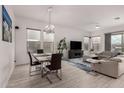 Bright living room with hardwood floors, a modern chandelier and a large sectional couch at 8751 S 168Th Dr, Goodyear, AZ 85338