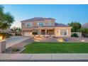 Charming two-story home with stone accents, well-lit landscaping, and a lush green lawn at 950 E Desert Inn Dr, Chandler, AZ 85249