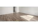 Bright living room featuring neutral walls and new hardwood-style laminate flooring at 5948 W Holly St, Phoenix, AZ 85035