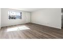 Bright living room featuring neutral walls and new hardwood-style laminate flooring at 5948 W Holly St, Phoenix, AZ 85035
