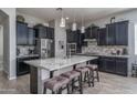 Modern kitchen with black cabinets, granite countertops, a large island, and stylish pendant lighting at 12158 S 184Th Ave, Goodyear, AZ 85338