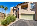 Three-story home with private balcony, two-car garage, desert landscaping, and palm trees set against a clear blue sky at 14575 W Mountain View Blvd # 621, Surprise, AZ 85374