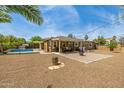 Spacious backyard featuring gravel landscaping, mature trees, a covered patio, and a grilling area at 18543 E Purple Sage Dr, Queen Creek, AZ 85142