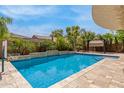 Gorgeous pool with a basketball hoop, surrounded by lush landscaping and stone tiling at 18543 E Purple Sage Dr, Queen Creek, AZ 85142