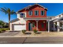 Charming two-story home features a red exterior with blue shutters and a well-manicured front yard at 399 N 157Th Ln, Goodyear, AZ 85338