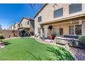 Backyard features an artificial grass lawn, covered patio with seating, and low-maintenance landscaping at 44235 W Mcclelland Dr, Maricopa, AZ 85138