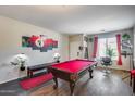 Bright game room boasts a red felt pool table, wood flooring, and a bench for seating, perfect for entertaining at 44235 W Mcclelland Dr, Maricopa, AZ 85138