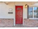 Close-up of the inviting red front door with brick trim and classic exterior lighting fixture at 4617 N 8Th Pl, Phoenix, AZ 85014