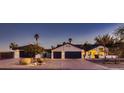 Charming home with three car garage, mature landscaping, and a well manicured front yard at dusk at 8755 E Gary Rd, Scottsdale, AZ 85260
