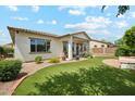 Manicured backyard featuring artificial turf, mature trees and a covered patio at 18001 W Cassia Way, Goodyear, AZ 85338