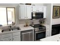 Well-lit kitchen features stainless steel appliances, white cabinets, and modern countertops at 1833 E Bluefield Ave, Phoenix, AZ 85022