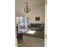 Cozy living room featuring tile floors, a chandelier, and a comfortable grey sofa at 1833 E Bluefield Ave, Phoenix, AZ 85022