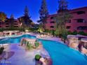 Community pool with landscaped rocks and trees at night, creating a resort-like atmosphere at 4303 E Cactus Rd # 407, Phoenix, AZ 85032