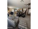 Open-concept living area with modern furnishings, neutral paint palette, with a view of the kitchen and stairs at 23236 W Yavapai St, Buckeye, AZ 85326